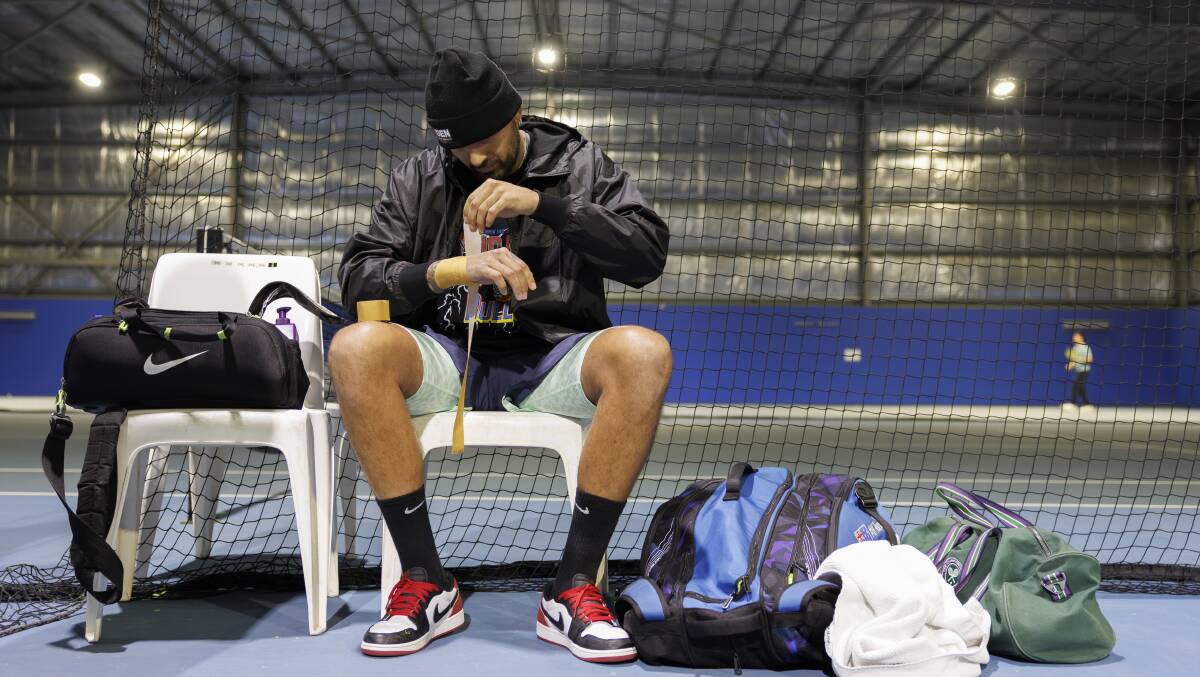 Nick Kyrgios tapes up his injured wrist before a hitting session. Picture by Keegan Carroll