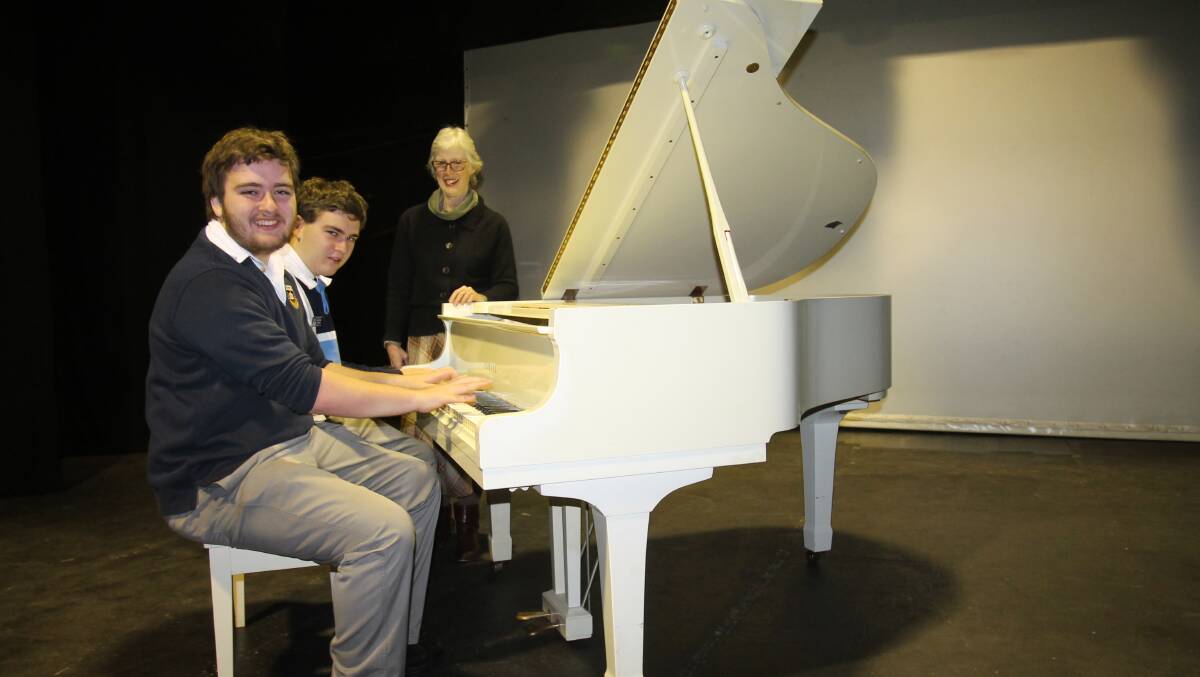 Twins William and Matthew Friend and their teacher for ten years, Alison Paterson, at the baby grand on which they will play at The Arts Centre on September 20.